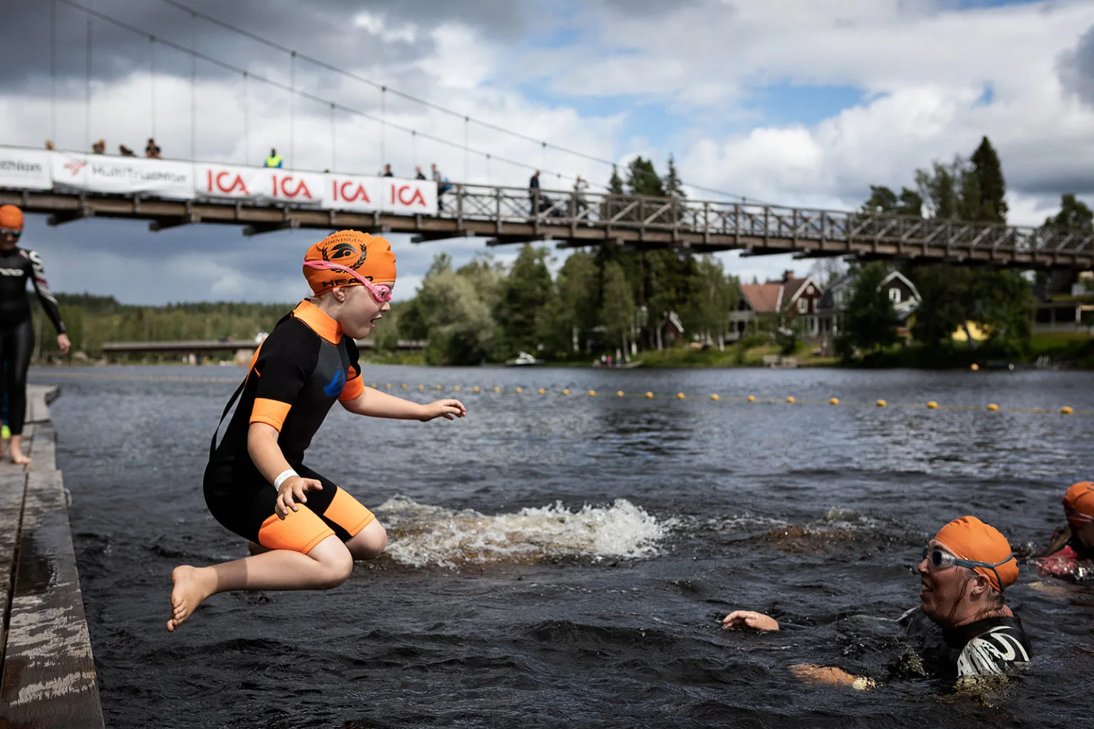 Ung flicka hoppar i vattnet från brygga.