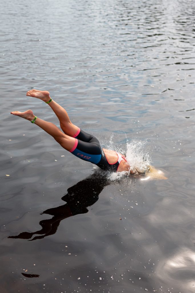 Kvinna dyker i vatten med simkläder.